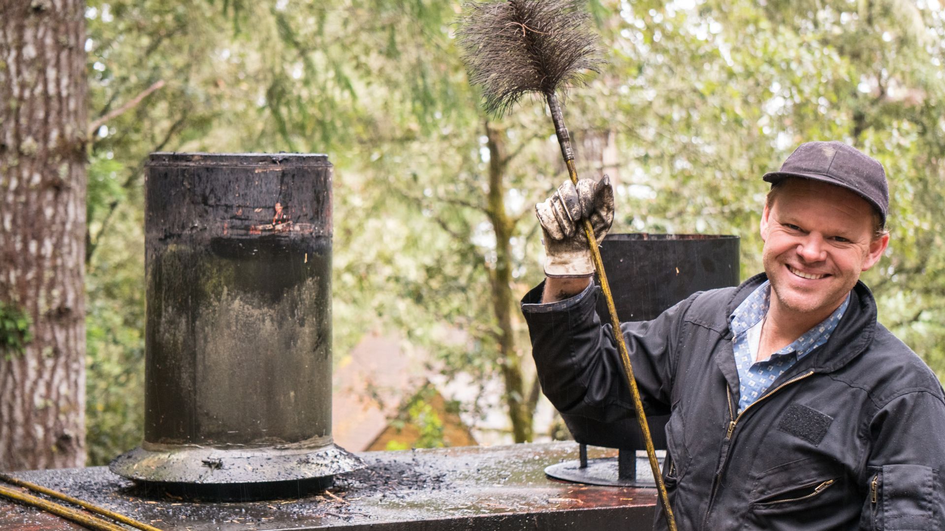 A worker happily holding a chimney cleaning tool